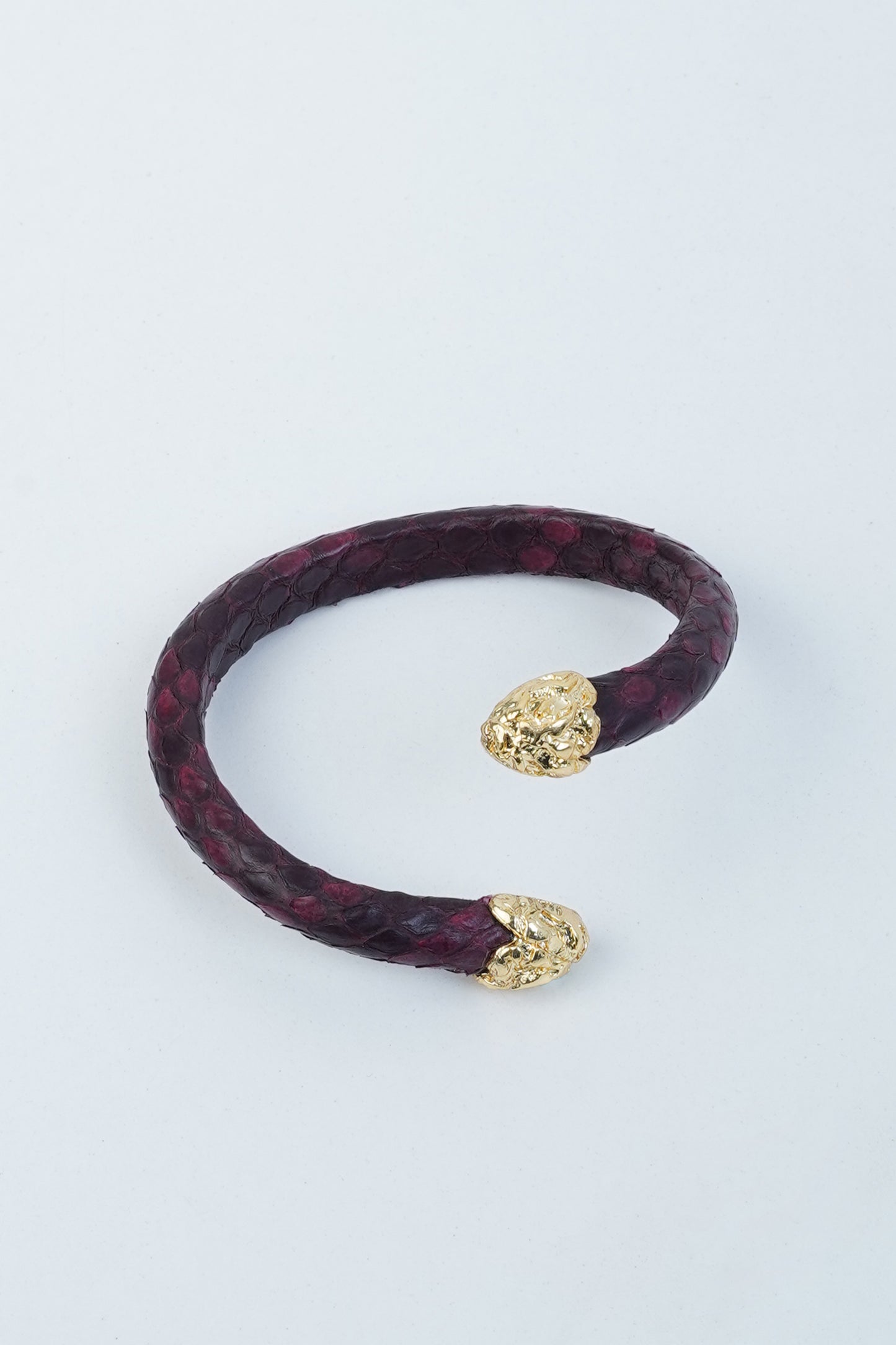 Handmade burgundy leather bracelet with gold-plated lion head ends, inspired by Hierapolis texture.