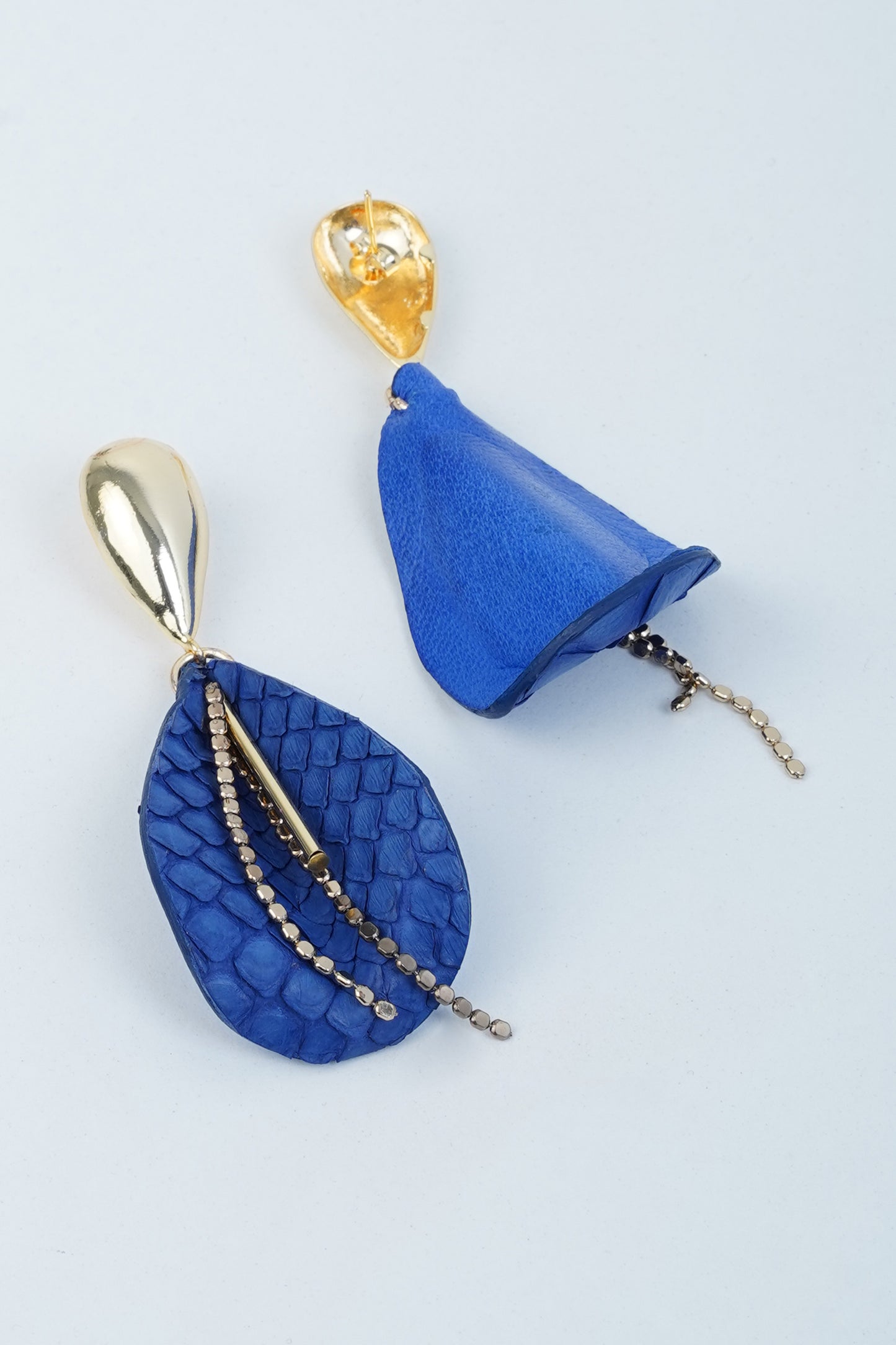 Pair of drop leaf earrings with blue leather and gold-plated brass details, featuring leaf and bell shapes