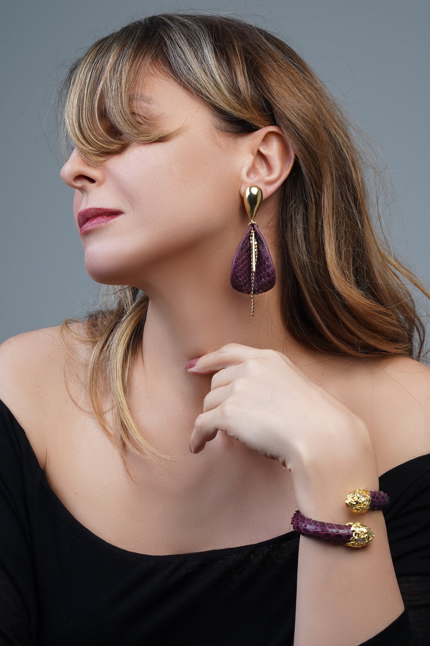 Gold-plated, burgundy-toned drop earrings featuring a leather-textured floral and leaf design with a dangling gold chain detail.